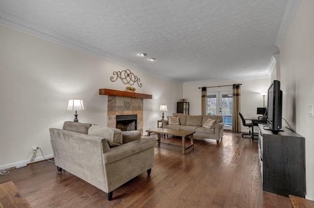 living area with dark wood-type flooring, baseboards, a tiled fireplace, ornamental molding, and a textured ceiling