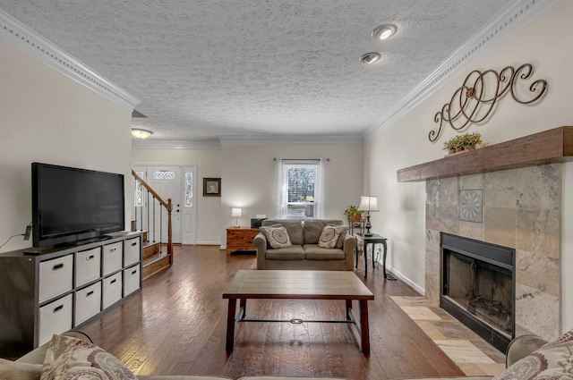 living room featuring stairway, a fireplace with flush hearth, hardwood / wood-style flooring, a textured ceiling, and crown molding
