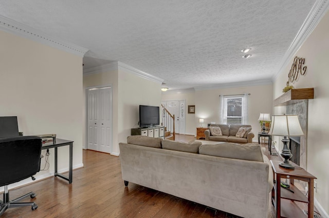 living room featuring ornamental molding, a textured ceiling, baseboards, and hardwood / wood-style flooring