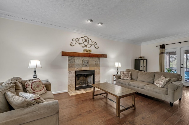 living room featuring crown molding, a tiled fireplace, french doors, wood finished floors, and a textured ceiling
