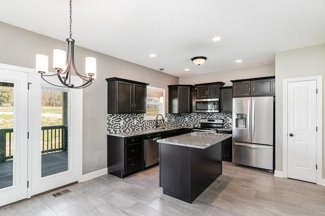 1033 Garner Hills Dr, Clarksville, TN 37042 - kitchen with visible vents, stainless steel appliances, a notable chandelier, tasteful backsplash, and a center island