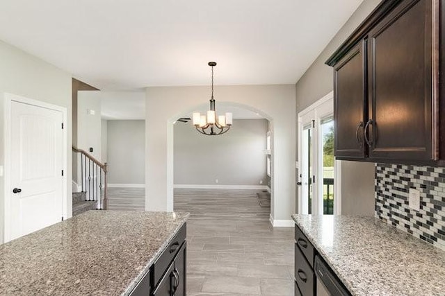 1033 Garner Hills Dr, Clarksville, TN 37042 - kitchen featuring dark brown cabinets, baseboards, light stone countertops, decorative backsplash, and an inviting chandelier