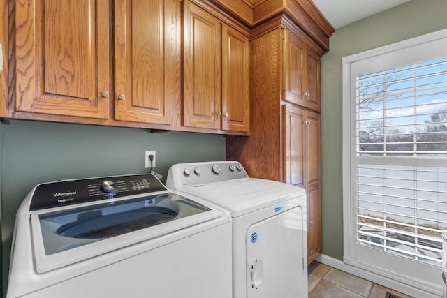 laundry area with light tile patterned floors, baseboards, cabinet space, and separate washer and dryer