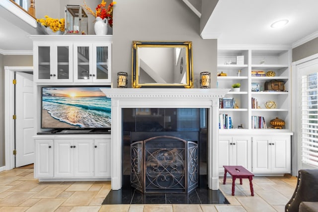 living area with stone finish floor, built in shelves, and ornamental molding