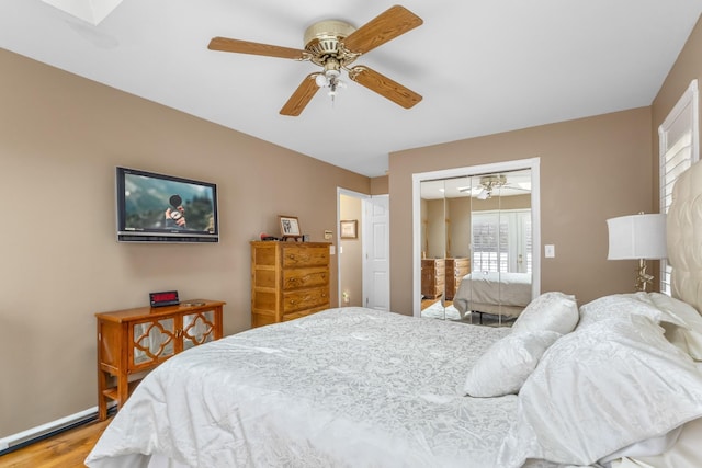 bedroom featuring light wood-type flooring, a closet, baseboards, and ceiling fan