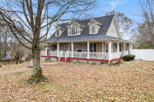 country-style home with fence, covered porch, and a shingled roof