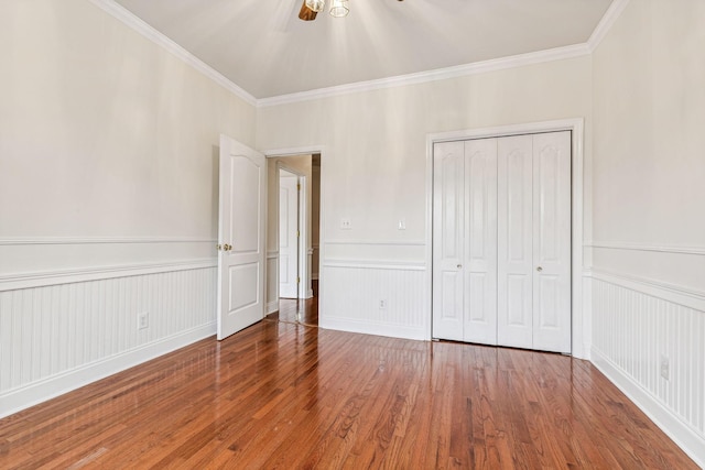 unfurnished bedroom with a wainscoted wall, hardwood / wood-style floors, and ornamental molding