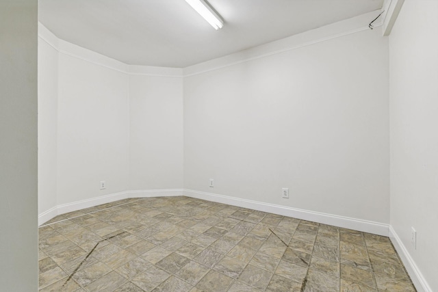 unfurnished room featuring stone finish flooring and baseboards
