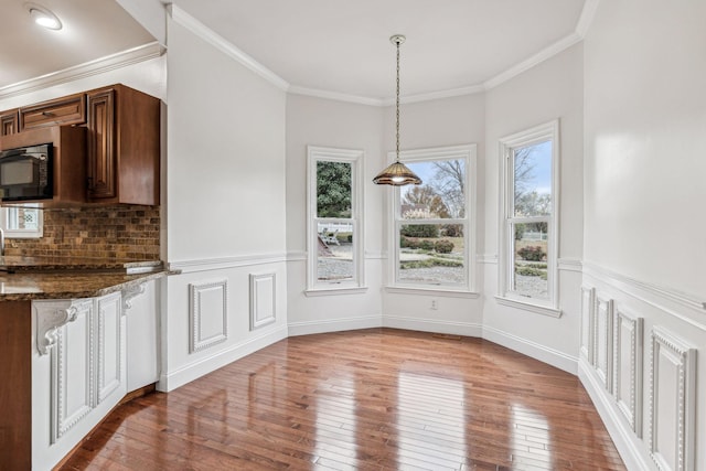 unfurnished dining area featuring hardwood / wood-style flooring, baseboards, and ornamental molding