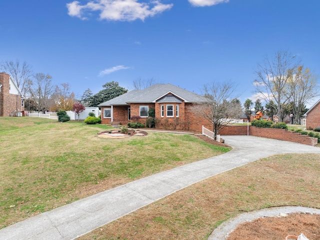 view of front of home featuring a front yard, fence, brick siding, and driveway