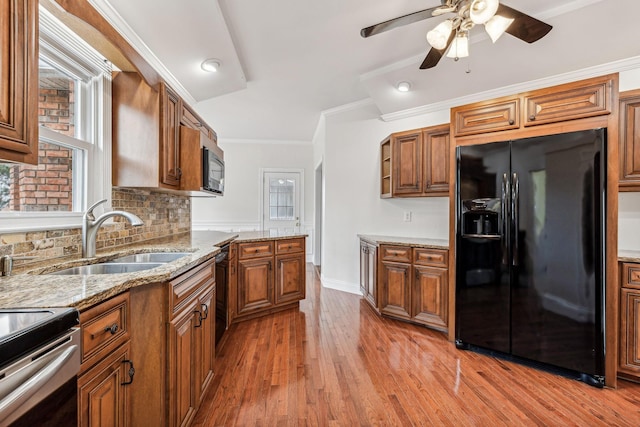 kitchen featuring crown molding, ceiling fan, brown cabinetry, black appliances, and a sink