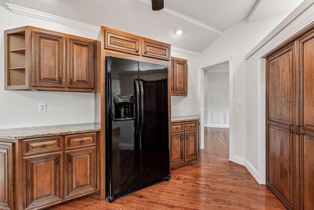 kitchen with light stone countertops, brown cabinetry, lofted ceiling, dark wood-type flooring, and black refrigerator with ice dispenser