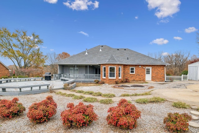 rear view of property with brick siding, a shingled roof, and fence