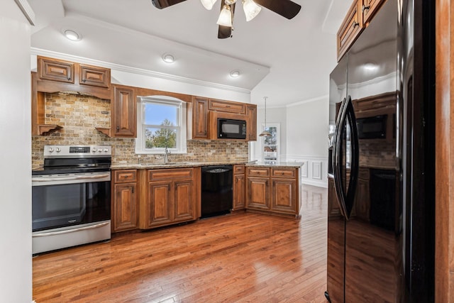 kitchen with ceiling fan, a peninsula, brown cabinetry, black appliances, and a sink