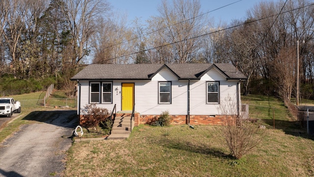 single story home featuring roof with shingles, a front lawn, and fence