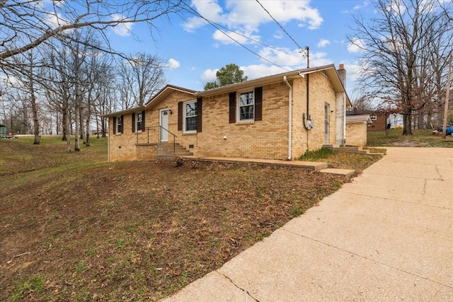 view of front of house with brick siding, a chimney, and concrete driveway