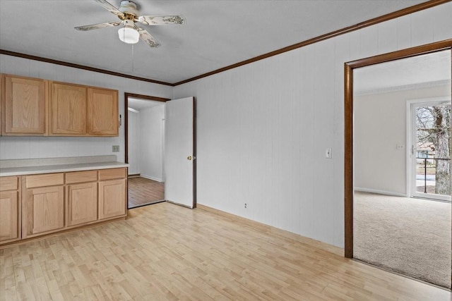 kitchen with crown molding, light countertops, light wood finished floors, and ceiling fan