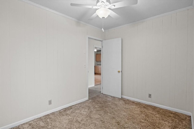 carpeted empty room with ceiling fan, baseboards, and ornamental molding