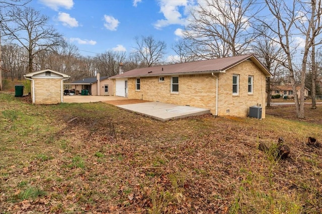 rear view of house featuring brick siding, crawl space, a patio area, and central AC