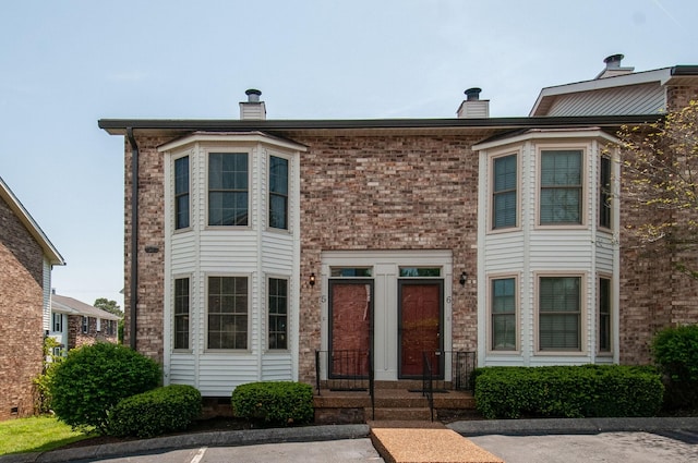 view of front of home with brick siding and a chimney