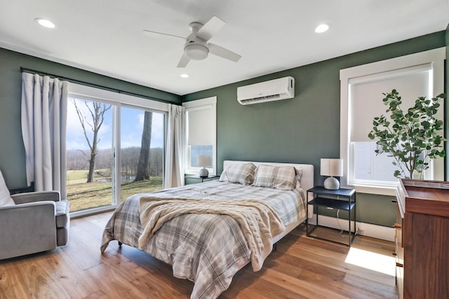 bedroom with a wall unit AC, wood finished floors, access to exterior, and recessed lighting