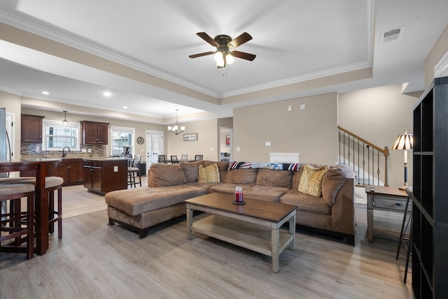 1561 Kestrel Dr, Clarksville, TN 37040 - living area with visible vents, ceiling fan with notable chandelier, light wood-style floors, a raised ceiling, and stairs