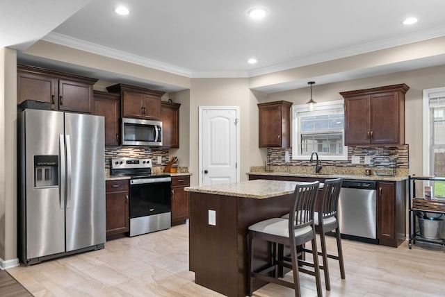 1561 Kestrel Dr, Clarksville, TN 37040 - kitchen featuring ornamental molding, dark brown cabinets, appliances with stainless steel finishes, and a center island