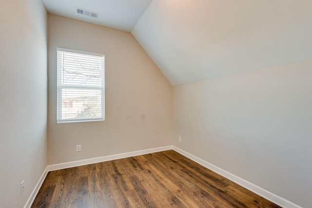 additional living space with visible vents, baseboards, dark wood-type flooring, and vaulted ceiling
