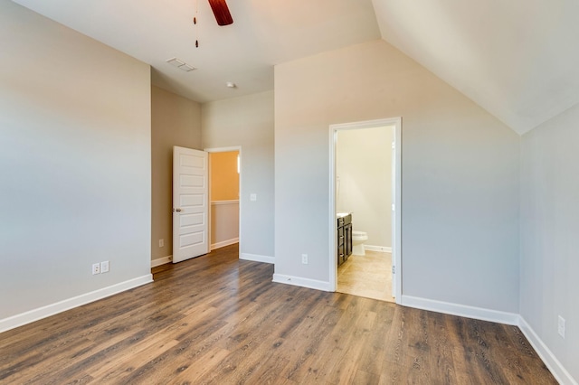 unfurnished bedroom featuring visible vents, ensuite bath, wood finished floors, baseboards, and vaulted ceiling