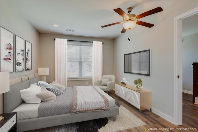 bedroom with a ceiling fan, wood finished floors, visible vents, and baseboards