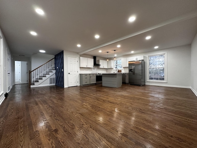 kitchen featuring dark wood-style floors, wall chimney range hood, stainless steel fridge with ice dispenser, and open floor plan
