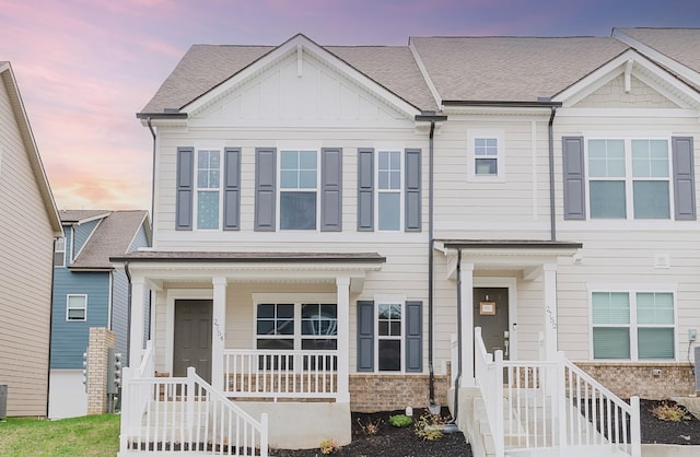view of front of property with board and batten siding, central AC unit, roof with shingles, and a porch