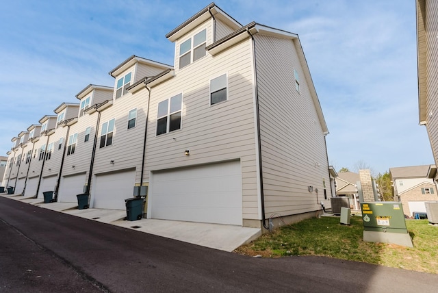 view of side of home with a garage, a residential view, and central AC unit