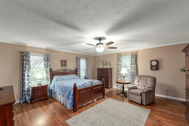 bedroom featuring wood finished floors, baseboards, ceiling fan, ornamental molding, and a textured ceiling