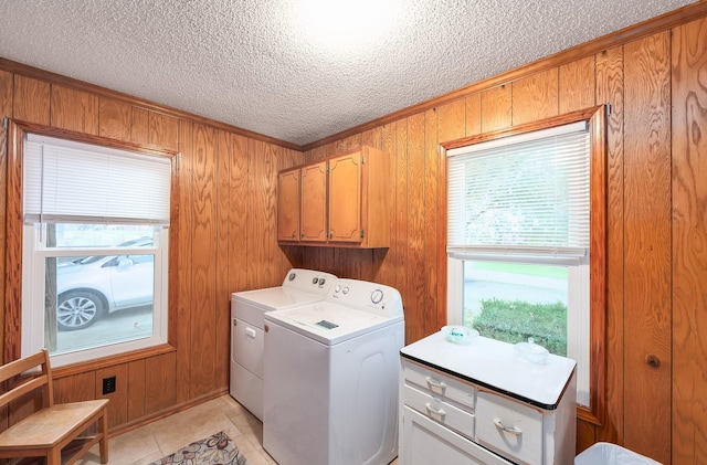 clothes washing area with independent washer and dryer, a textured ceiling, cabinet space, wood walls, and light tile patterned floors