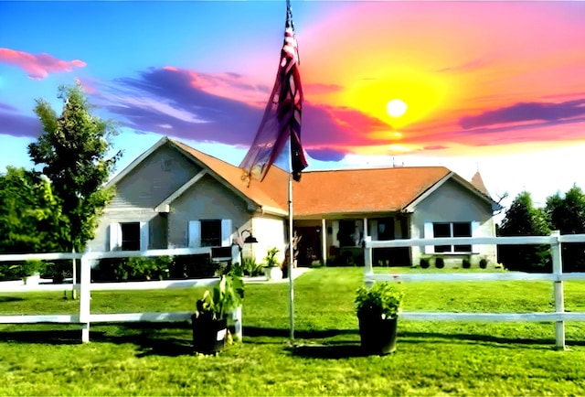 rear view of house with fence and a lawn