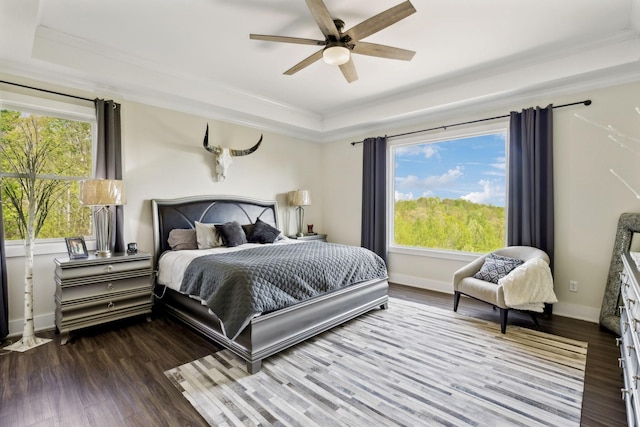 bedroom featuring a raised ceiling, crown molding, wood finished floors, and baseboards