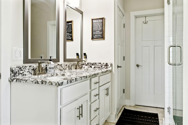 full bath featuring a shower stall, double vanity, and a sink