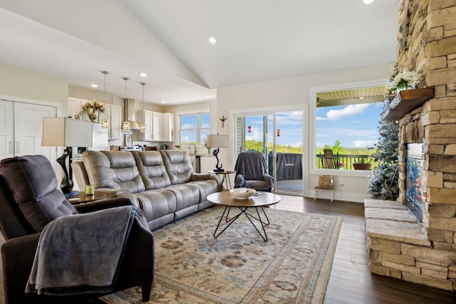 living area with recessed lighting, a fireplace, dark wood-type flooring, and high vaulted ceiling
