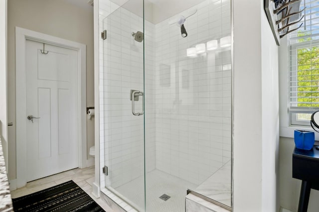 bathroom featuring marble finish floor and a stall shower