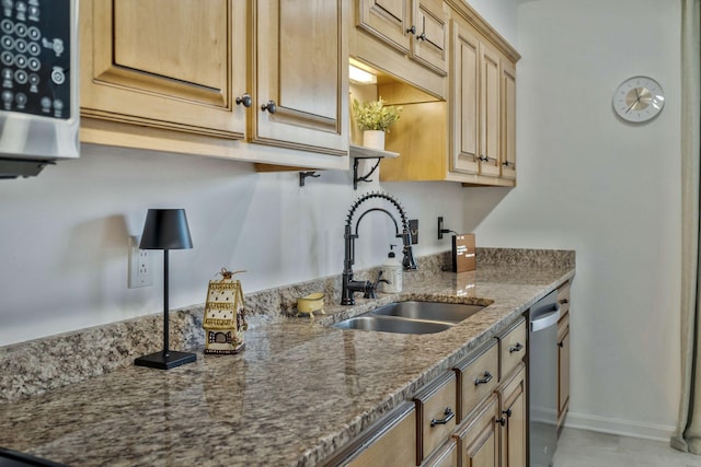 kitchen with dishwasher, baseboards, stone countertops, and a sink