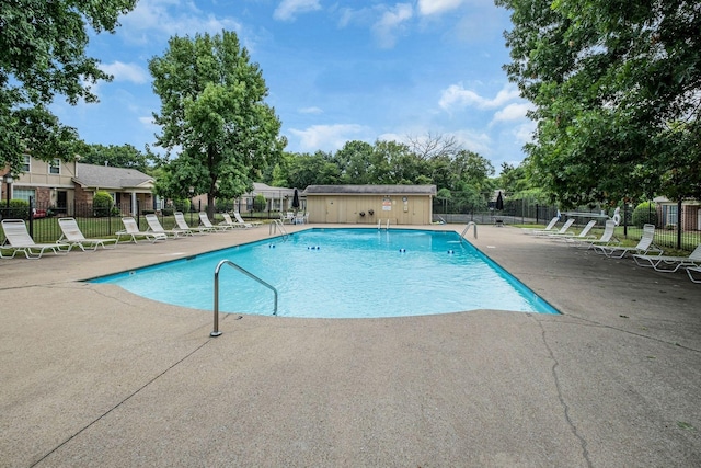 community pool with a patio area and fence
