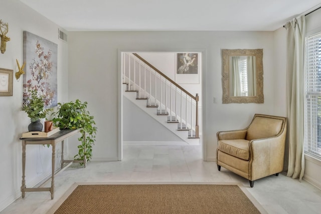 foyer with light tile patterned floors, visible vents, stairway, and baseboards