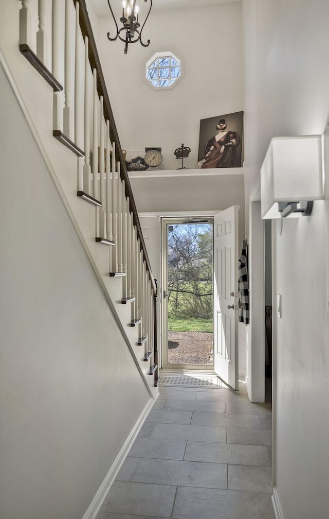 foyer entrance with a high ceiling, a healthy amount of sunlight, a chandelier, and stairs