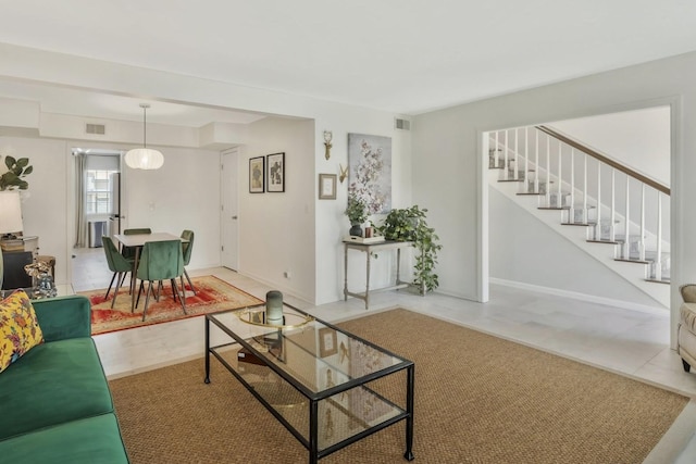 living room with stairway, baseboards, and visible vents