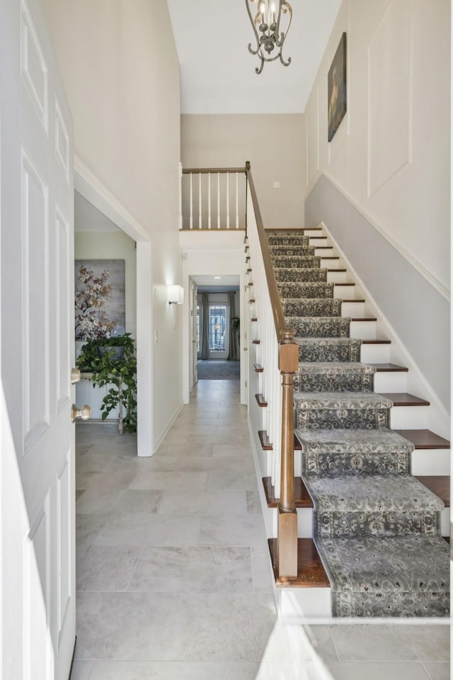 foyer entrance featuring a high ceiling, an inviting chandelier, and stairs