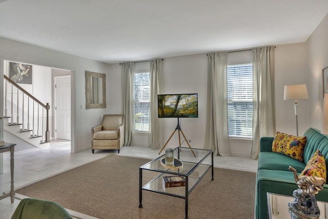 living area featuring tile patterned floors, a healthy amount of sunlight, stairs, and baseboards