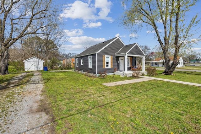 bungalow with an outdoor structure, driveway, a detached garage, a front lawn, and covered porch