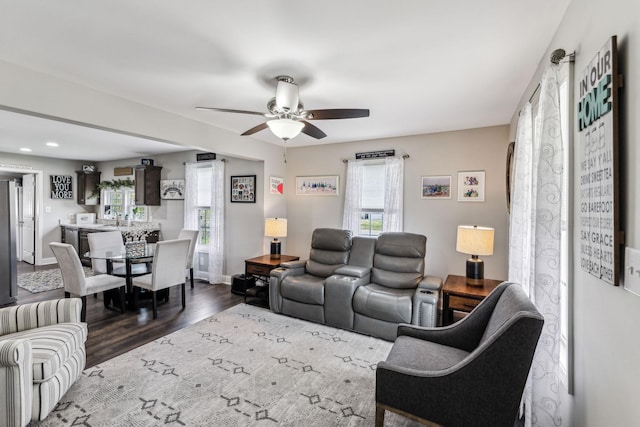living area with a ceiling fan, baseboards, and wood finished floors