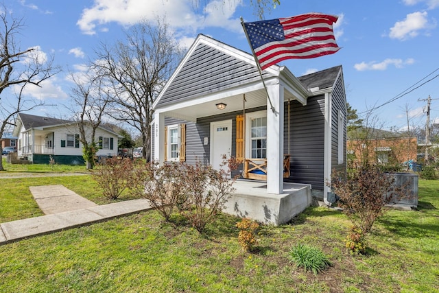 view of front facade with covered porch, central AC unit, and a front yard